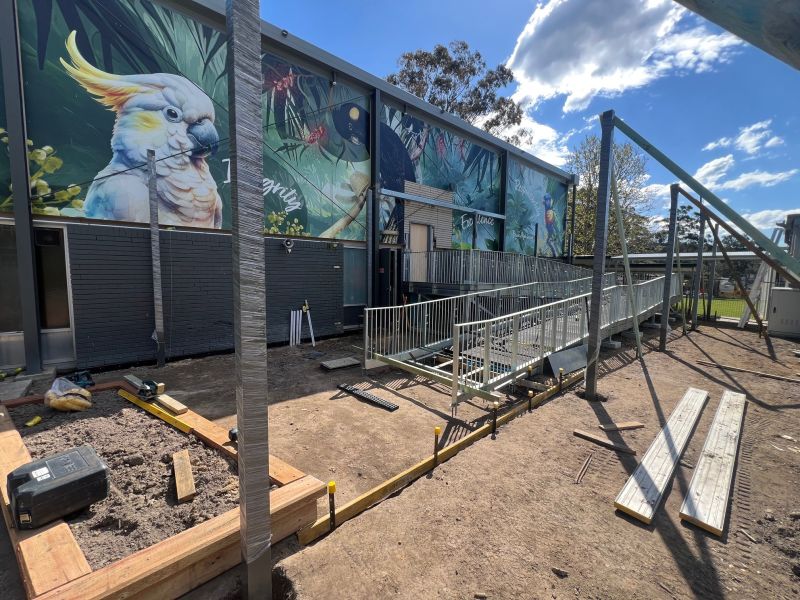 Accessibility upgrade in progress beside a new ramp and a school mural