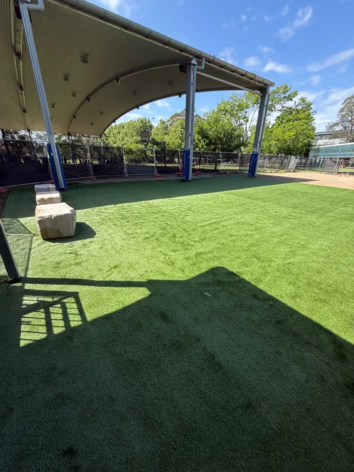 Synthetic grass running under the covered outdoor area, with sandstone block seats