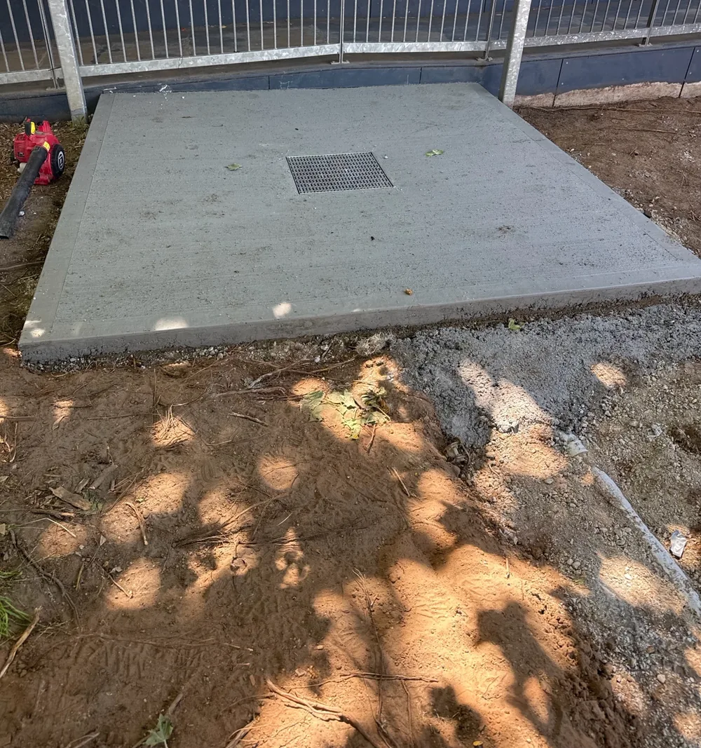 New concrete pad with a stormwater grate beside the walkway ramp